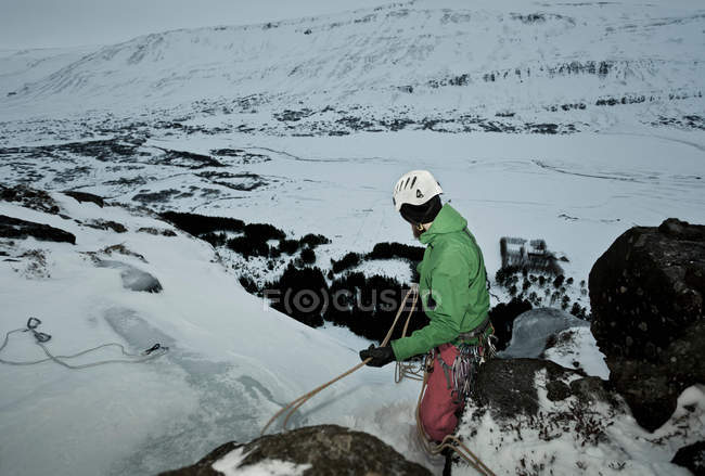 Escalador com corda na colina nevada — Fotografia de Stock