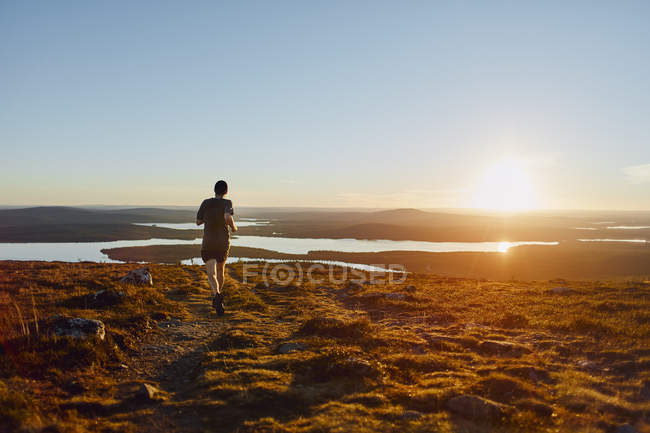 Man Trail läuft bei Sonnenuntergang auf Klippen, keimiotunturi, Lappland, Finnland — Stockfoto