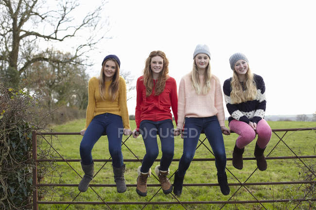 Четыре девочки-подростка сидят на воротах — стоковое фото