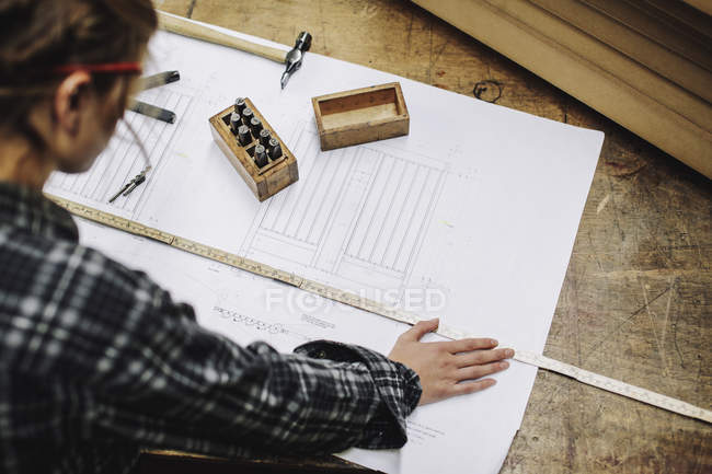 Young craftswoman measuring blueprint in pipe organ workshop — Stock Photo