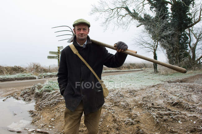 Portrait of mature farmer holding pitchfork — Stock Photo