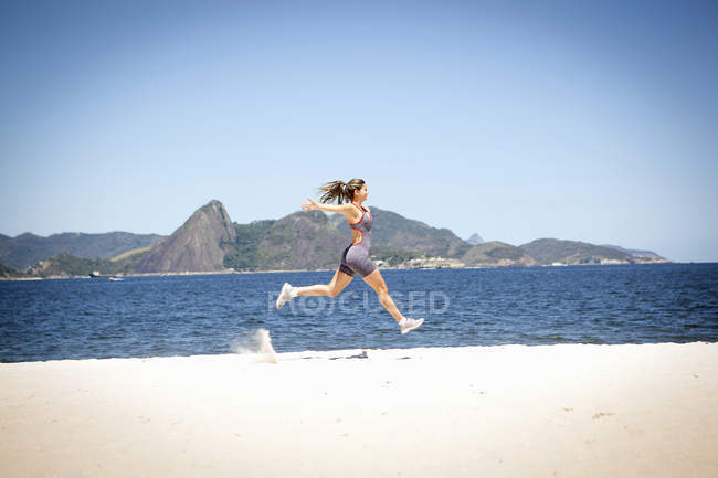 Young woman jumping on beach, Rio de Janeiro, Brazil — Stock Photo