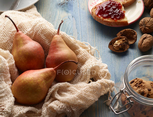 Bodegón de peras, galletas, nueces y pan con mermelada en la mesa - foto de stock