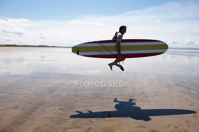 Male surfer jumping with board — Stock Photo