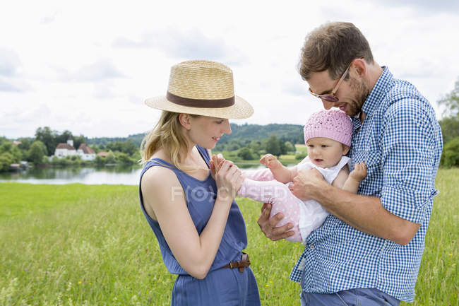 Parents holding baby daughter in field — Stock Photo