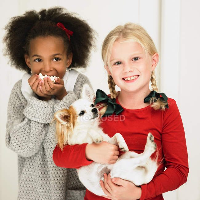 Girls eating popcorn and holding dog — Stock Photo
