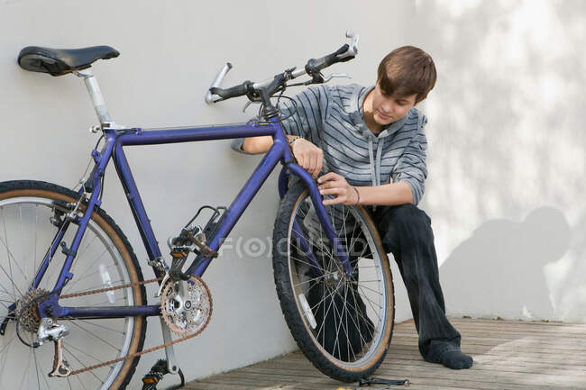 Мальчик-подросток ремонтирует велосипед — стоковое фото
