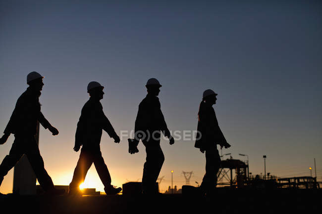 Silueta de los trabajadores de la refinería de petróleo - foto de stock
