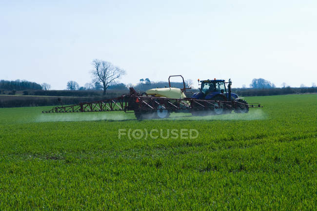 Tractor pulling mechanics in crop field — Stock Photo