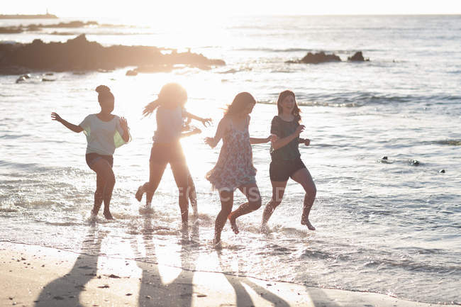 Mujeres corriendo juntas en la playa - foto de stock