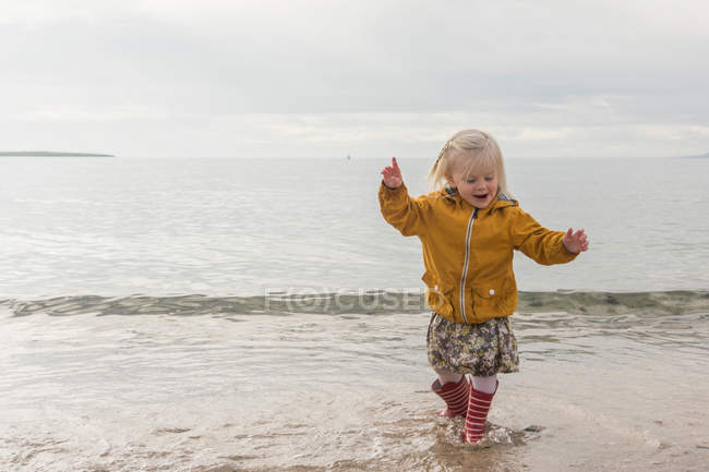 Criança caminhando na água na costa — Fotografia de Stock