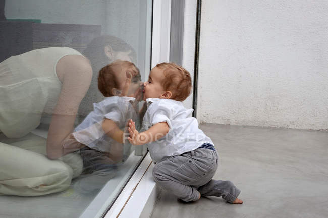 Madre e hijo besándose a través del vidrio - foto de stock