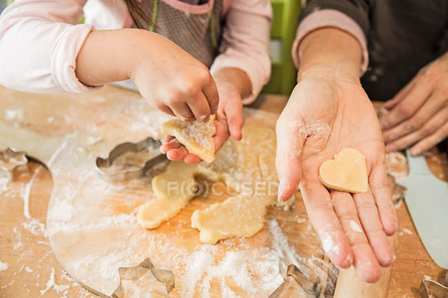 Руки матери и дочери пекут печенье на кухне — стоковое фото