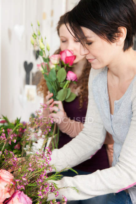 Woman and teenage girl choosing flowers in florists — Stock Photo