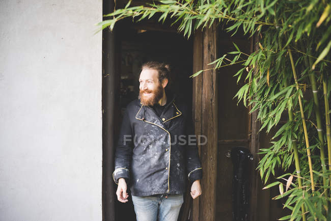 Бородатий чоловік стоїть у дверях, дивлячись геть усміхнений — стокове фото