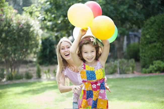 Мать и дочь играют в саду с воздушными шарами — стоковое фото