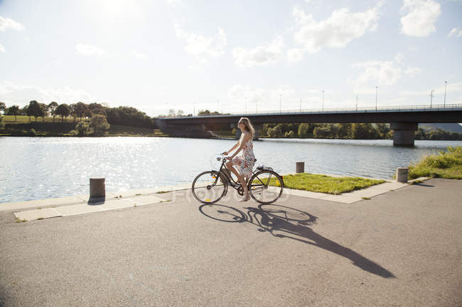 Молодая женщина на велосипеде на берегу реки, остров Дунай, Вена, Австрия — стоковое фото