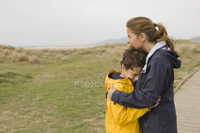 Madre e hijo abrazándose en el paseo marítimo - foto de stock