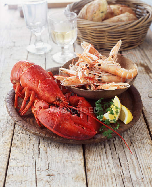 Plate of lobster and prawns with wicker basket of bread — Stock Photo