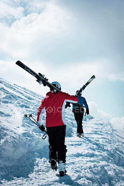 Blick von hinten auf Skifahrer, die den schneebedeckten Berghang erklimmen — Stockfoto