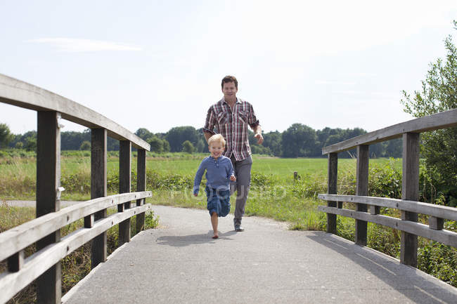 Father and son running on wooden bridge — Stock Photo