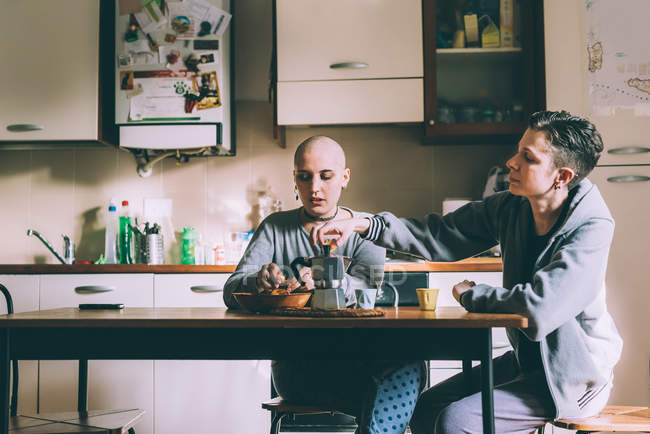 Jovem casal lésbico derramando café expresso na cozinha — Fotografia de Stock