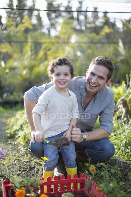 Portrait of mid adult man and son gardening in allotment — Stock Photo