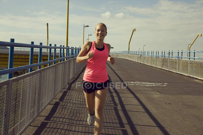 Молода жінка біжить через міст — стокове фото