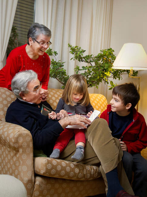 Casal mais velho com netos no sofá — Fotografia de Stock