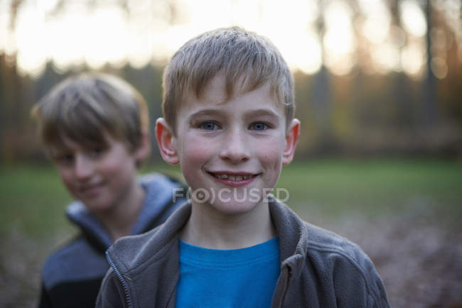 Retrato de chicos mirando en cámara en bosque en retroiluminación - foto de stock