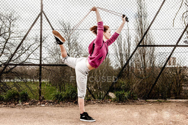 Жінка в светрі тягне пілатес мотузка ззаду зігнутої ноги — стокове фото