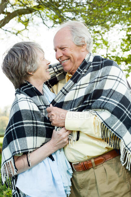 Senior couple wrapping in shawl together — Stock Photo