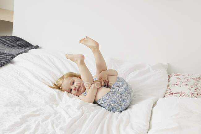 Porträt einer Kleinkindfrau, die auf dem Bett spielt — Stockfoto