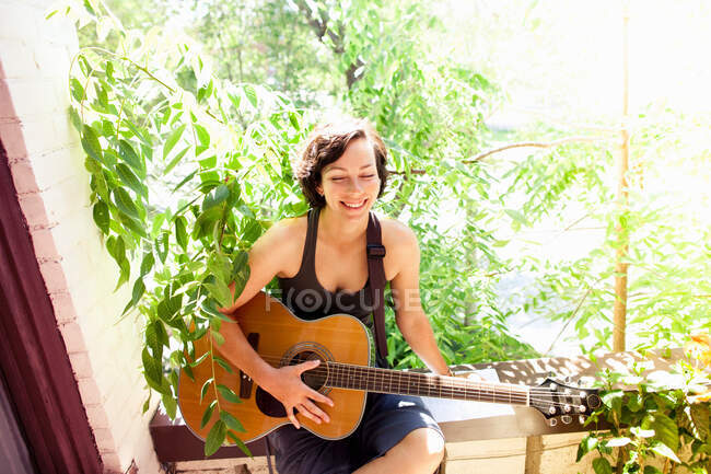Frau spielt Gitarre auf Balkon — Stockfoto