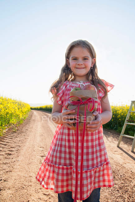 Chica llevando manzanas en camino de tierra - foto de stock