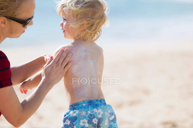 Mother rubbing sunscreen on daughter — Stock Photo