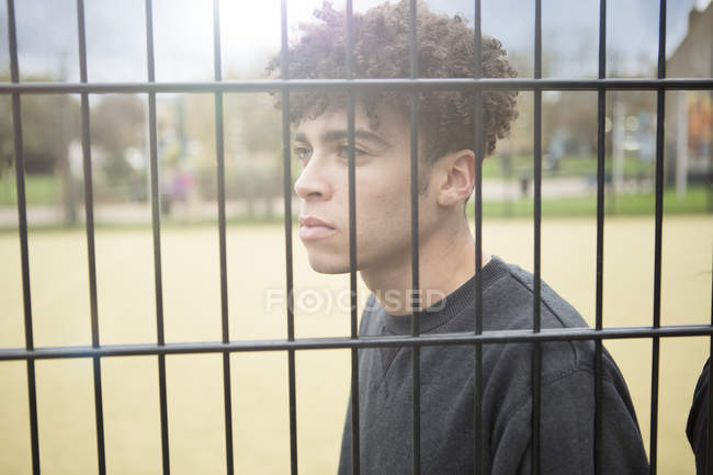 Junger Mann lehnt an Zaun — Stockfoto