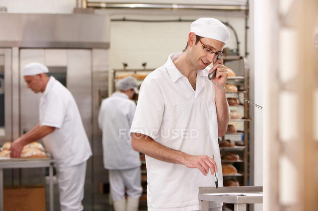 Chef talking on phone in kitchen — Stock Photo