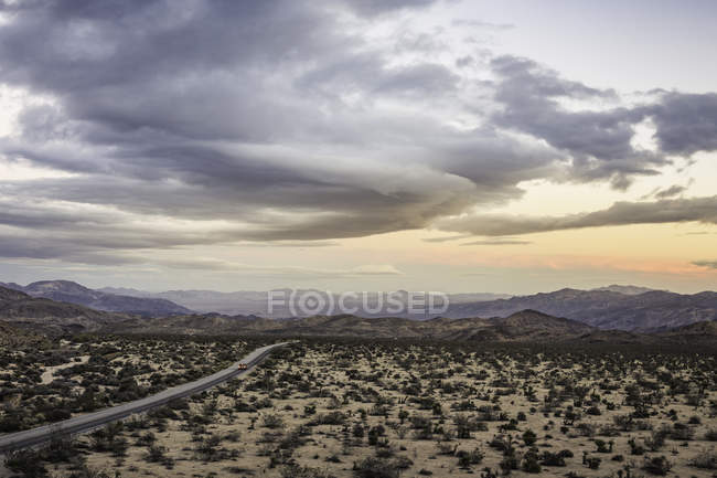 Veduta panoramica di un'autostrada lontana nel parco nazionale di Joshua Tree al crepuscolo, California, Stati Uniti — Foto stock