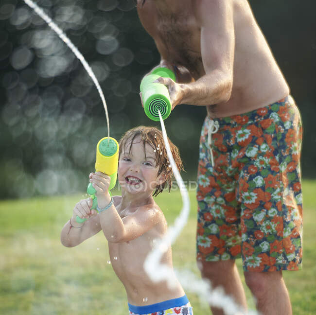 Father and son having fun with water gun — Stock Photo