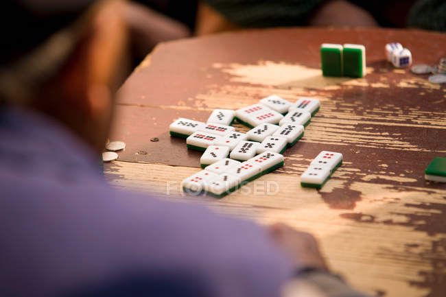 Ritagliato colpo di uomo che gioca domino su tavolo rustico in legno — Foto stock