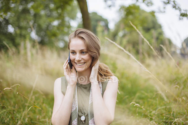 Young woman chatting on smartphone in field — Stock Photo
