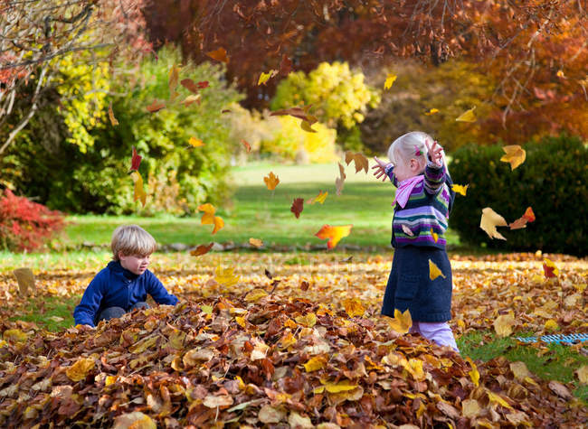 Bambini che giocano in mucchio di foglie — Foto stock