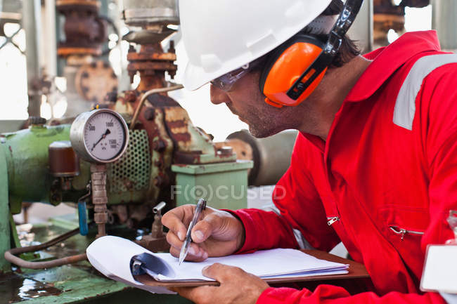 Arbeiter notiert Messgerät in Ölraffinerie — Stockfoto