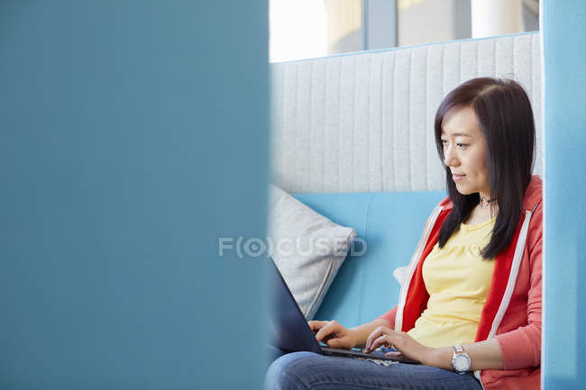 Estudiante universitario usando laptop en cubículo moderno - foto de stock