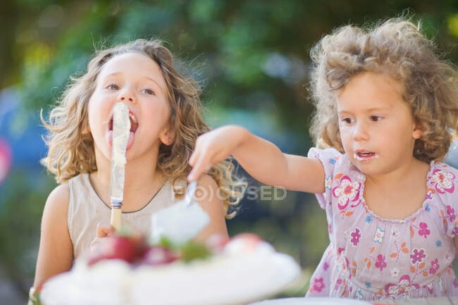 Дівчата ріжуть торт на відкритому повітрі. — стокове фото