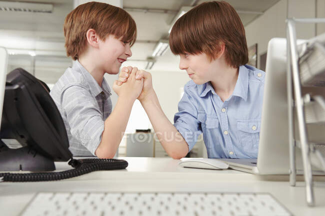 Two boys arm wrestling in office — Stock Photo