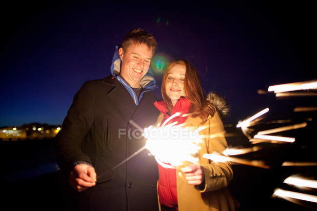 Couple playing with sparklers on beach — Stock Photo