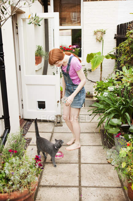 Mulher alimentando gato no quintal — Fotografia de Stock