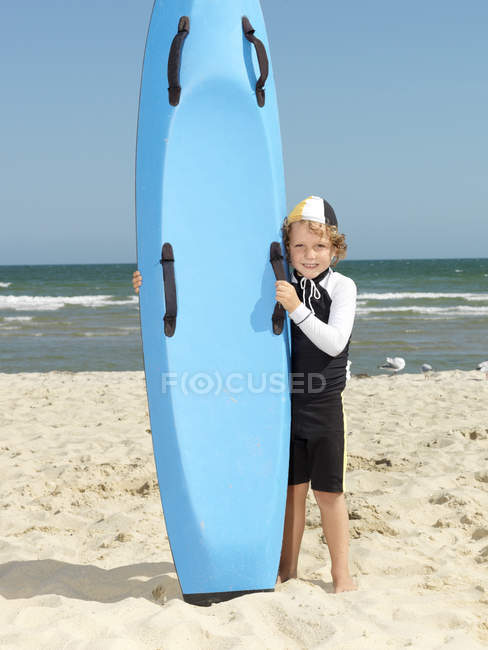Ritratto di simpatico ragazzo pinza (salvagente di surf bambino) accanto alla tavola da surf in spiaggia, Altona, Melbourne, Australia — Foto stock